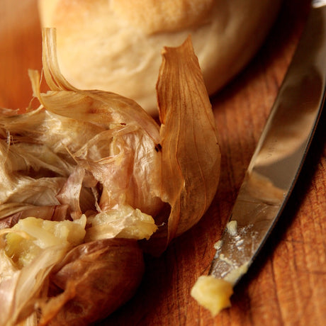 A whole roasted smoked garlic on wooden board straight from the oven