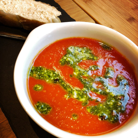 A bowl of tomato & chilli soup served with smoked pesto and crusty bread