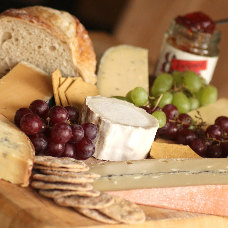 Smoked cheeses on board with grapes, cheese crackers & chutney