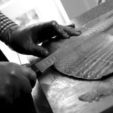 A whole smoked salmon being hand sliced on board