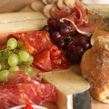 Slices of The Artisan-Smokehouse's smoked Spianata Calabra salami on meat platter with other smoked meats, bread and grapes