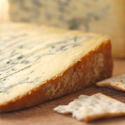 A piece of smoked Stilton on cheese board with crackers