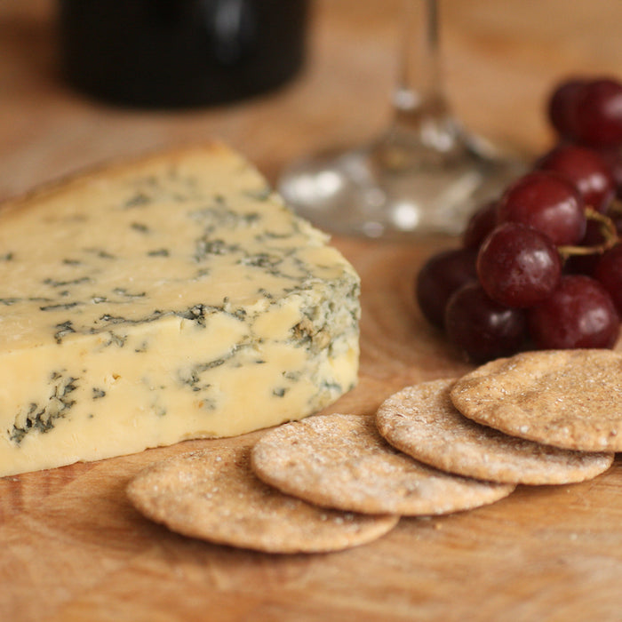 A piece of smoked Stilton on cheese board with crackers and grapes